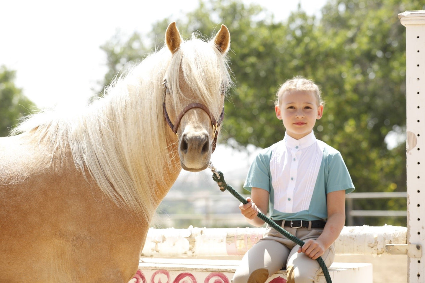 Kids equestrian riding show shirt from Cavalleria Toscana holding pony.