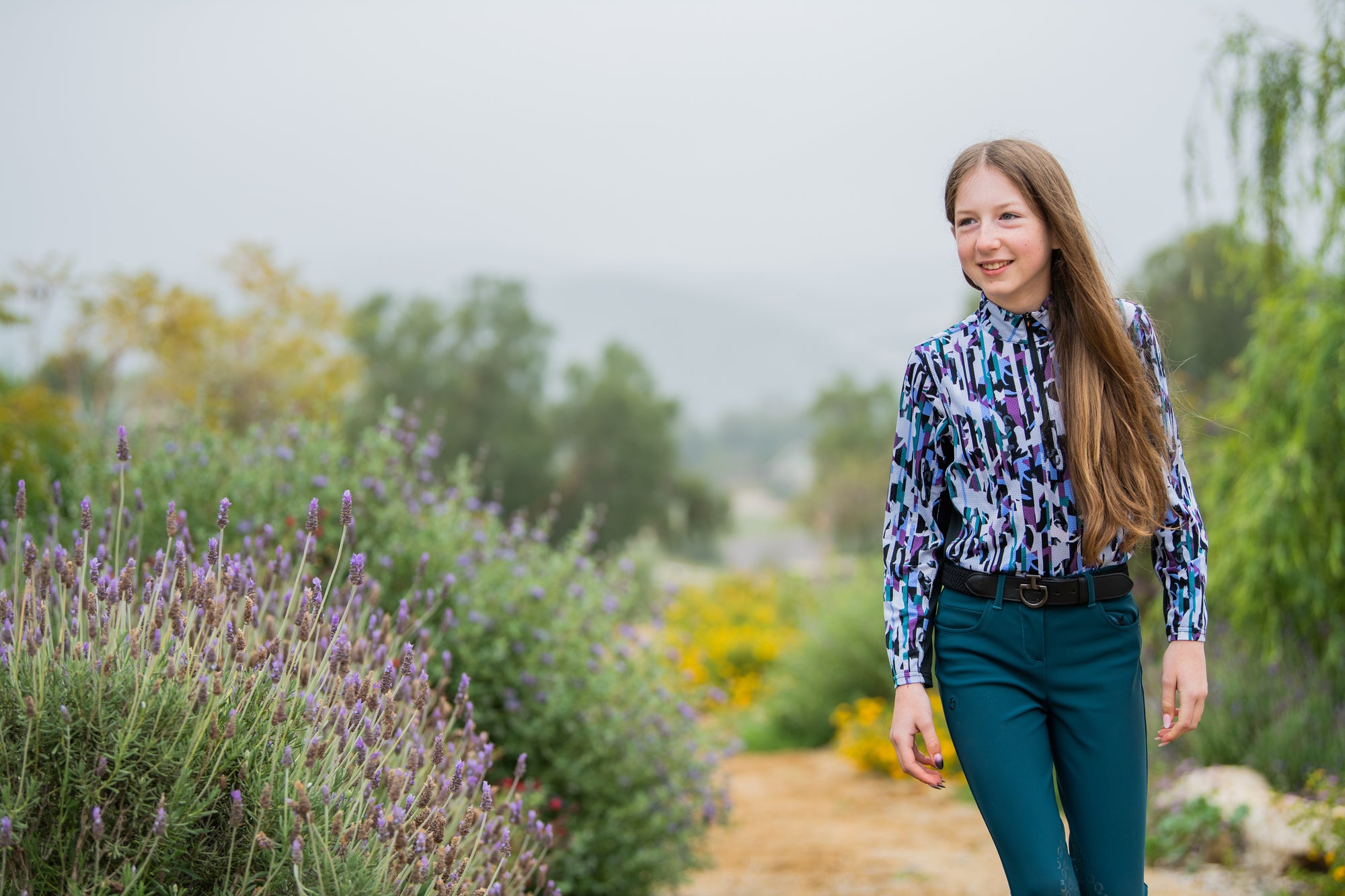 Equestrian brunette girl wearing a pattern shirt in a field of flowers!