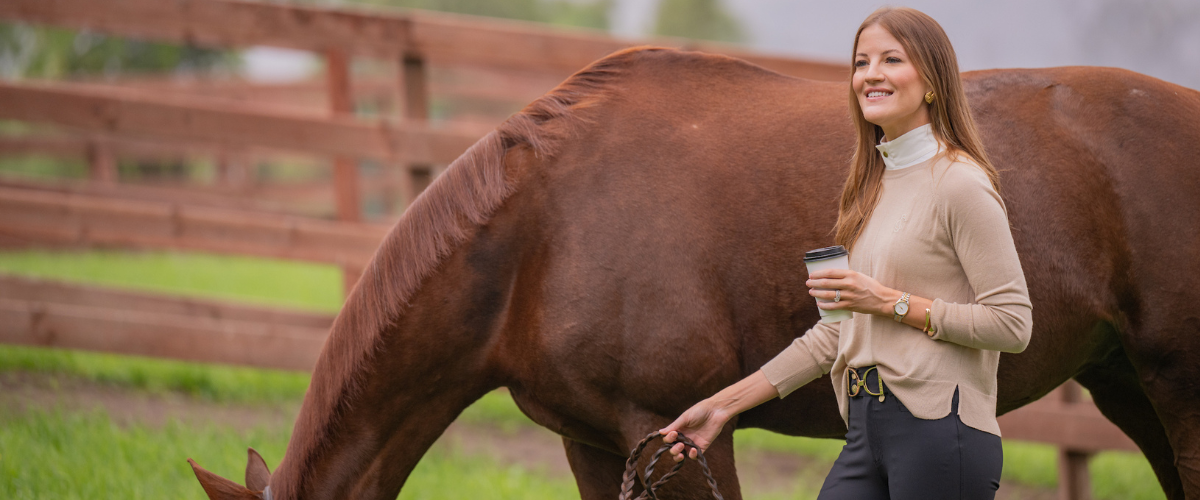 Girl in sunshirt holding hand to horse with bridle